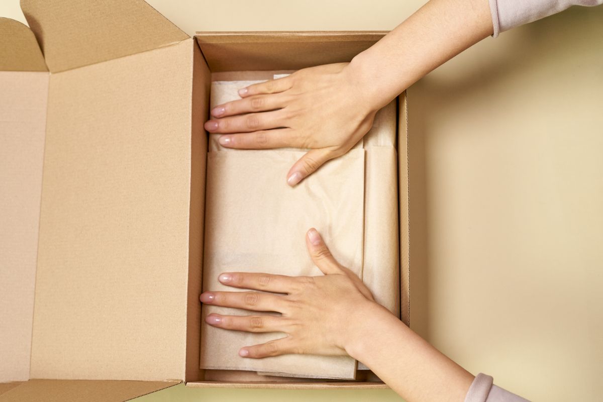 Hands packing a tissue-wrapped item into a box